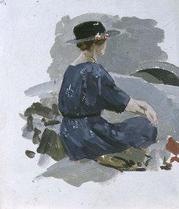 Woman in a blue dress and wide brimmed hat sitting upon rocks